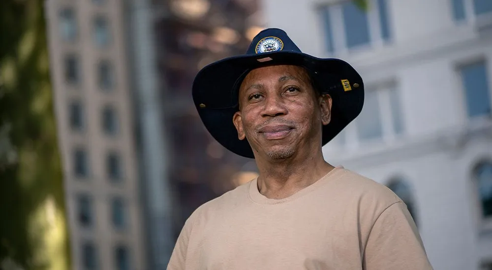Article image: a Veteran in a wide-brimmed hat outside a city building.