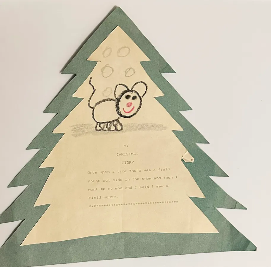 A childhood Christmas story typed on paper and mounted on a green paper Christmas tree, illustrated with a crayon drawing of a field mouse. The story reads: “Once upon a time there was a field mouse out side in the snow and then I went to my mom and I said I saw a field mouse.”