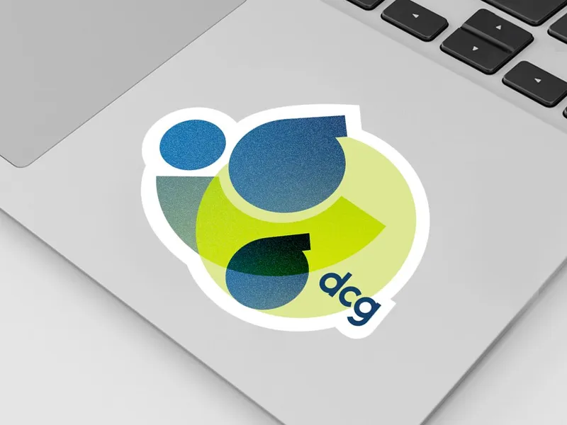 The rebranded dcg mark — overlapping navy and lime shapes beside the lowercase wordmark — as a die-cut sticker on a laptop lid.
