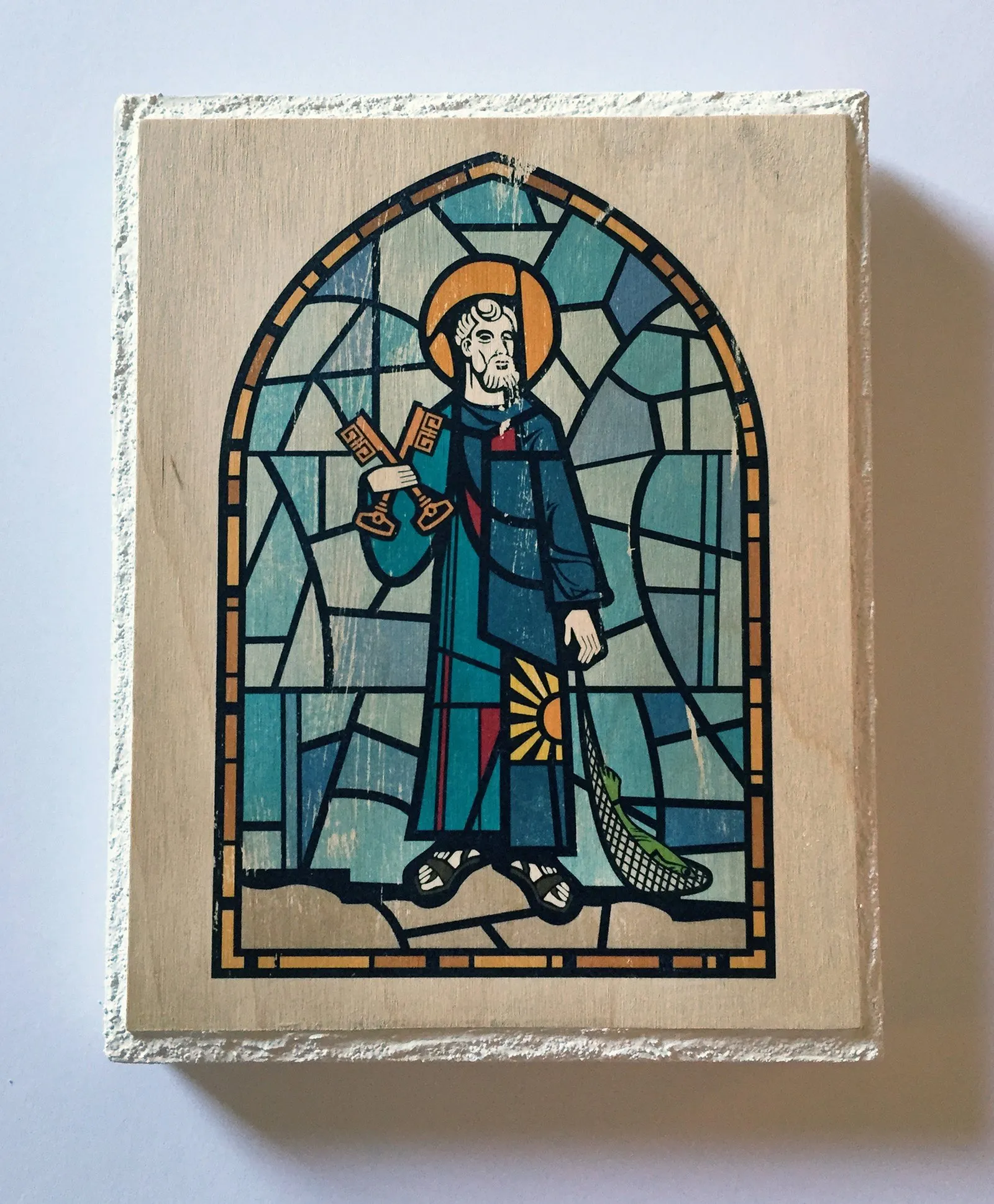 A stained-glass-style Saint Peter, holding his keys and a net, transferred onto a raw wood panel.