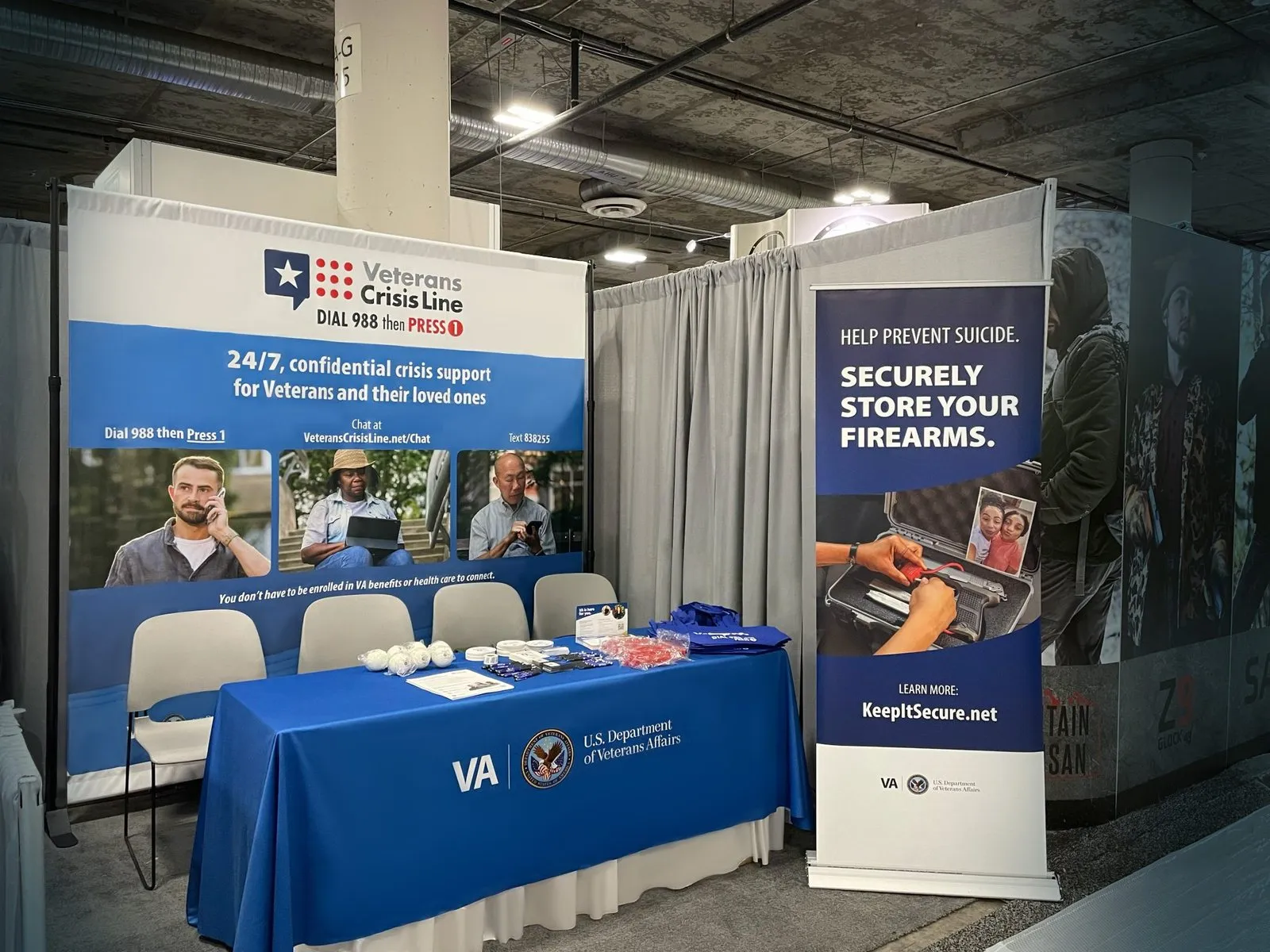 The VA booth at the 2024 Shot Show: navy table covers, roll-up banners and a firearm storage display.