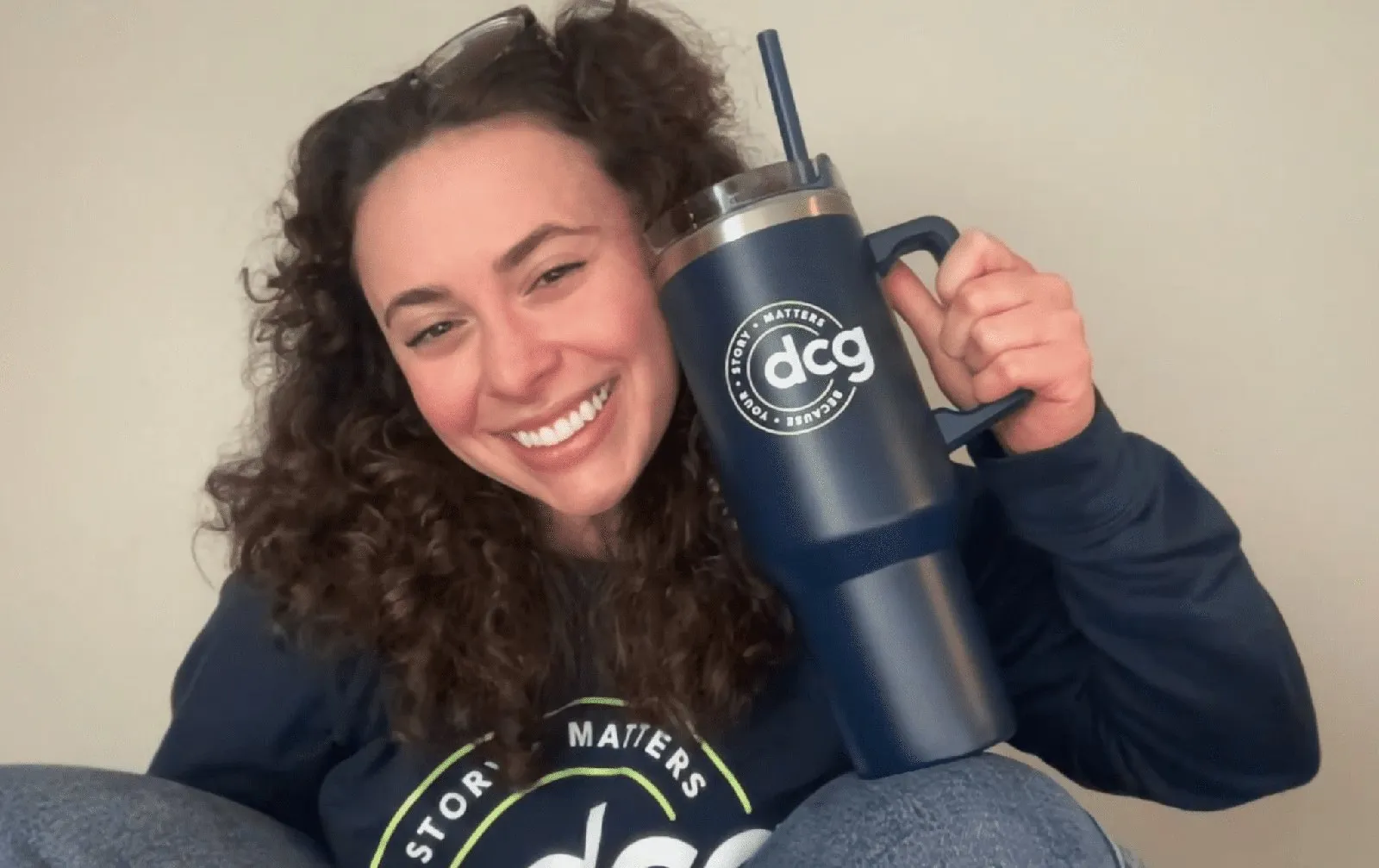 Kristen holding a navy dcg tumbler, wearing a dcg “Your story matters” sweatshirt.